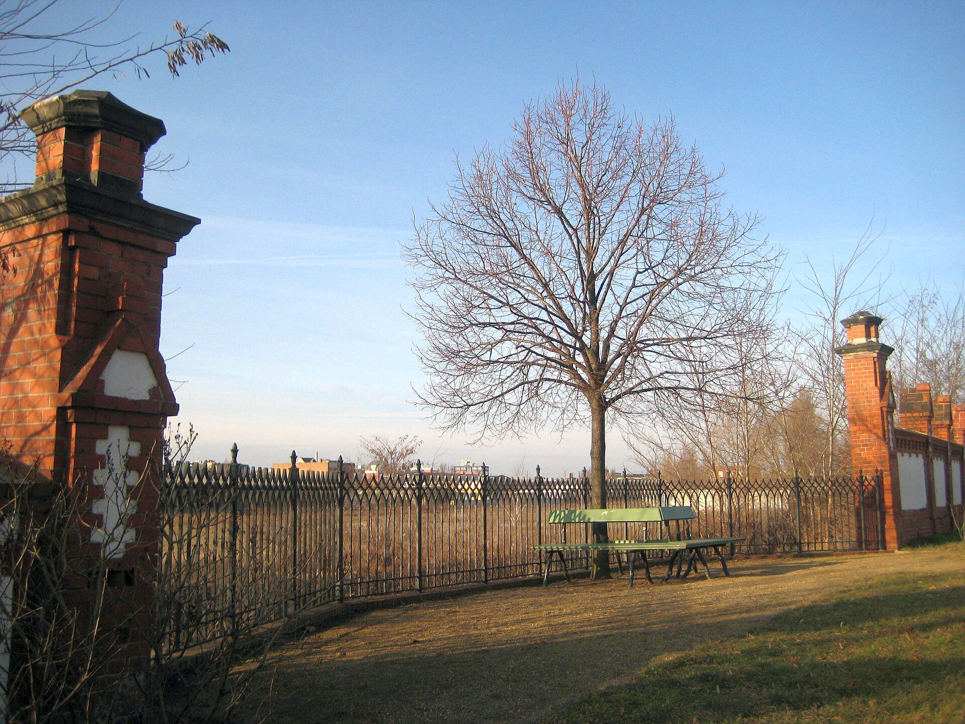 Rekonstruierte rote Ziegelmauer, eisernes Gitter und Königslinde am Invalidenfriedhof